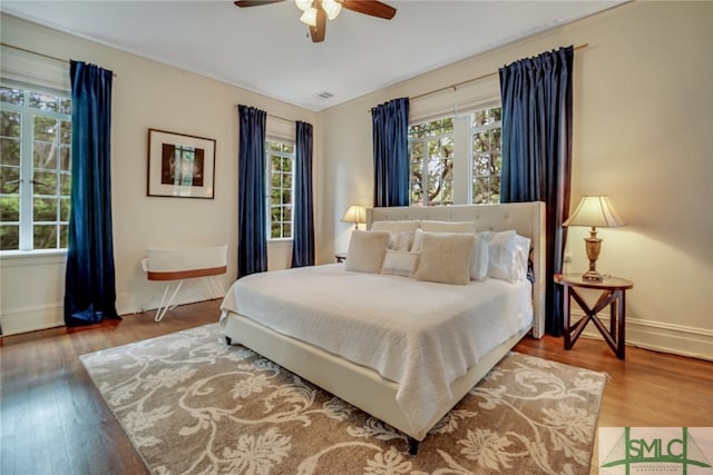 bedroom with visible vents, wood finished floors, baseboards, and ceiling fan