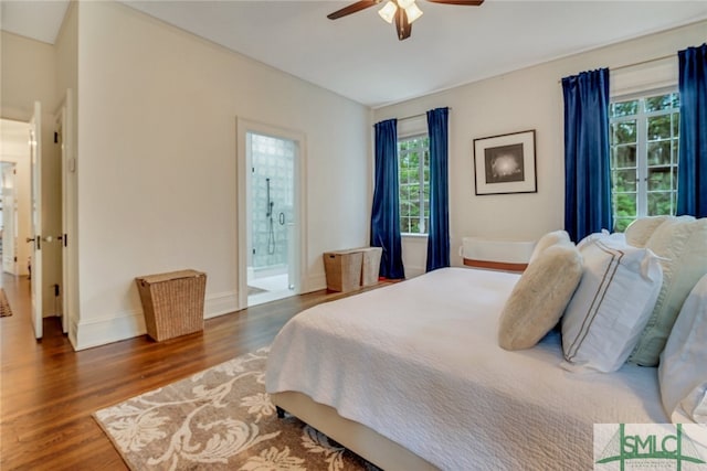 bedroom featuring a ceiling fan, ensuite bath, wood finished floors, and baseboards