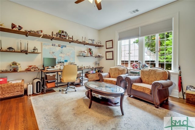 interior space with visible vents, built in desk, wood finished floors, and a ceiling fan