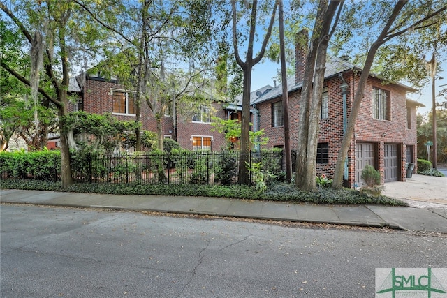 view of front of house featuring a fenced front yard, brick siding, a garage, and a chimney