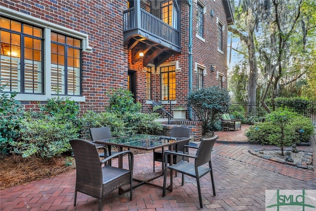 view of patio with a balcony, outdoor dining area, and fence