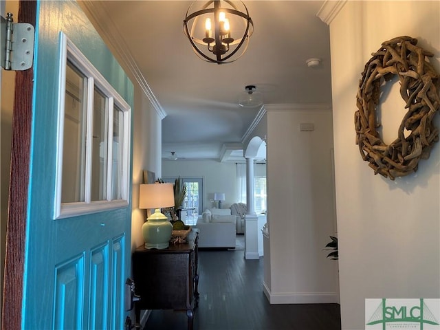 entryway featuring ornamental molding, wood finished floors, baseboards, a chandelier, and ornate columns