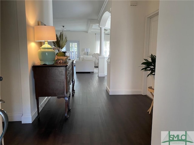 hall with decorative columns, baseboards, and dark wood-type flooring