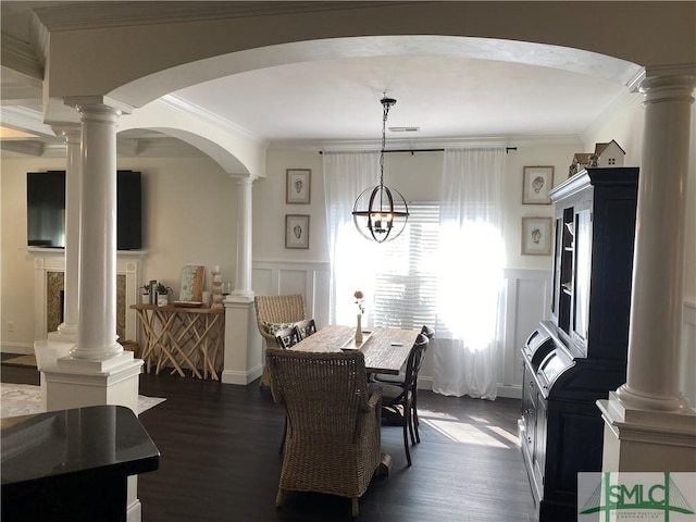 dining room featuring decorative columns, dark wood-type flooring, ornamental molding, and a decorative wall