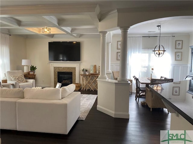 living room with crown molding, dark wood-type flooring, beamed ceiling, decorative columns, and a decorative wall