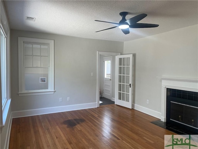 unfurnished living room featuring a fireplace, wood finished floors, visible vents, and baseboards