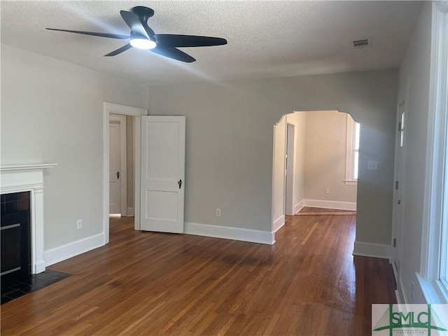 unfurnished living room featuring visible vents, a tile fireplace, ceiling fan, and wood finished floors