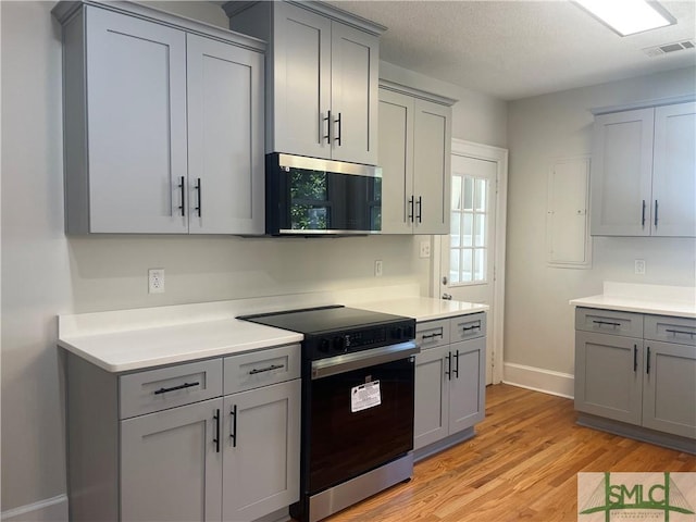 kitchen with electric range, light wood-style floors, visible vents, and gray cabinets