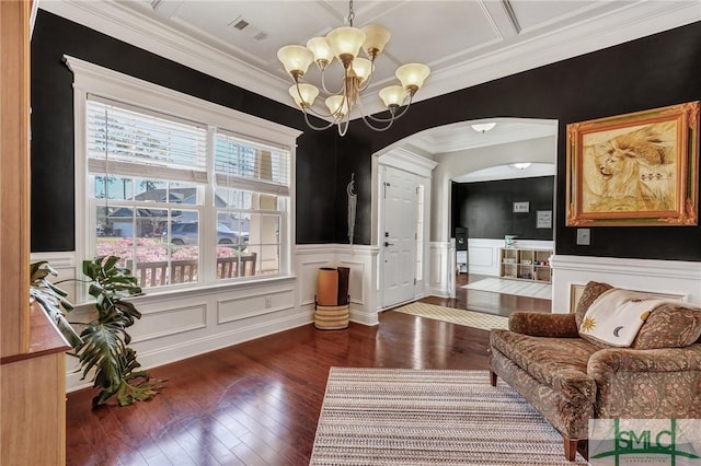 living area with hardwood / wood-style floors, visible vents, an inviting chandelier, arched walkways, and ornamental molding