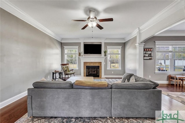 living area with baseboards, wood finished floors, a tile fireplace, and ceiling fan