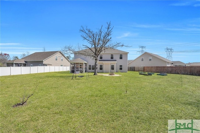 view of yard with a fire pit, a fenced backyard, and a sunroom