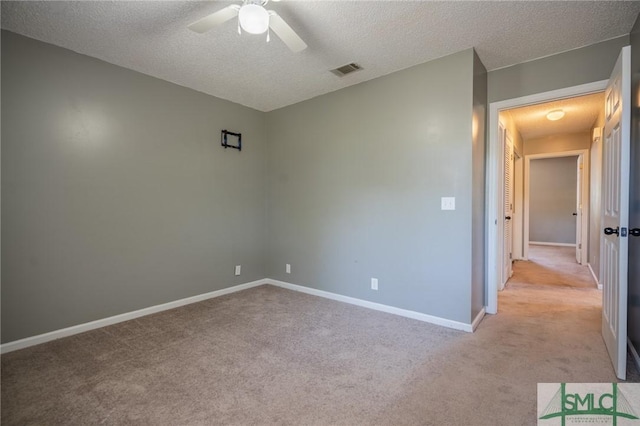 unfurnished bedroom featuring light carpet, visible vents, a textured ceiling, and baseboards