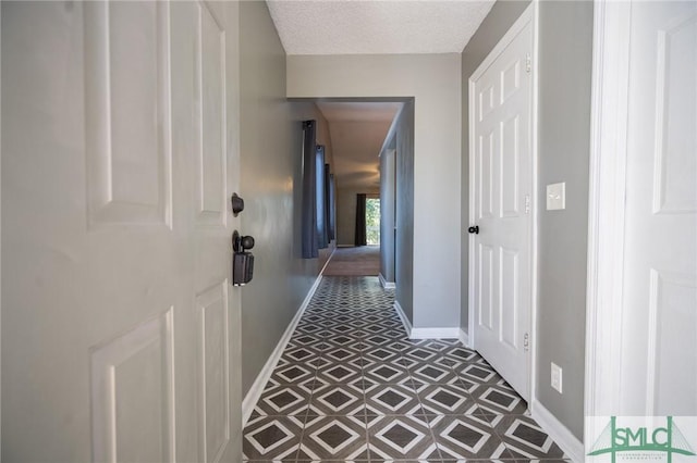 hallway with a textured ceiling and baseboards