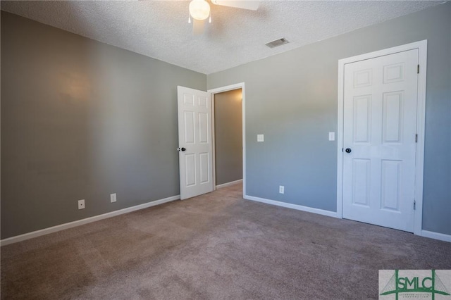 unfurnished bedroom featuring visible vents, carpet flooring, a textured ceiling, and baseboards