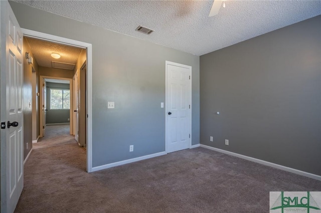 unfurnished bedroom with visible vents, carpet floors, a textured ceiling, and baseboards