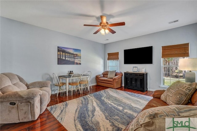 living room featuring baseboards, wood finished floors, visible vents, and ceiling fan