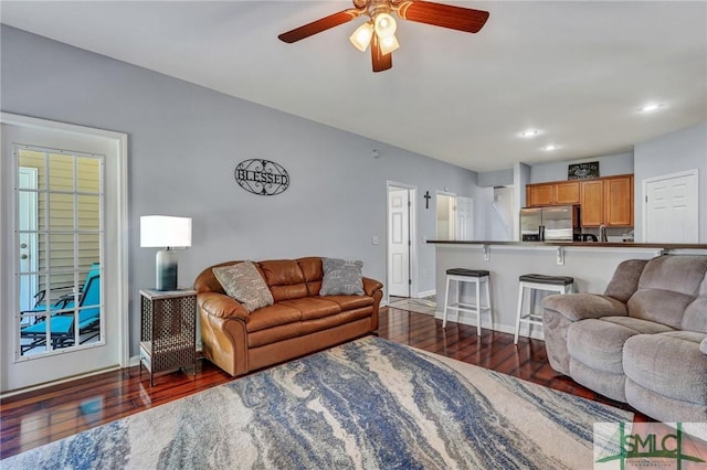 living room with baseboards, dark wood-style floors, and a ceiling fan