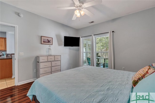 bedroom featuring ceiling fan, visible vents, baseboards, and wood finished floors