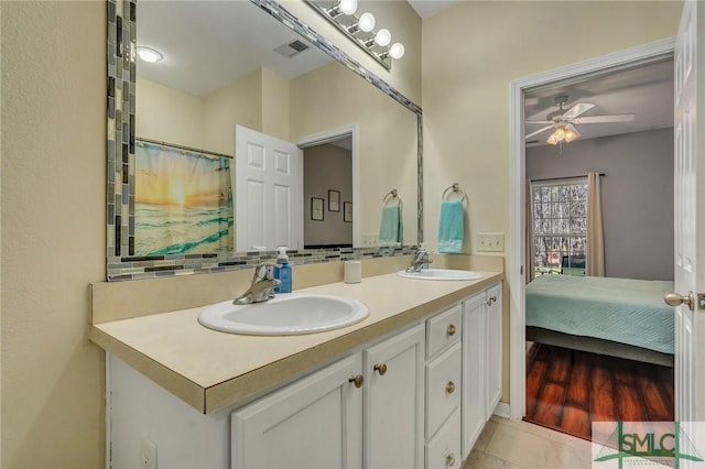 bathroom featuring a sink, backsplash, ceiling fan, and double vanity