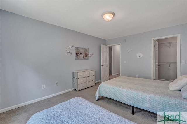 carpeted bedroom with a walk in closet and baseboards