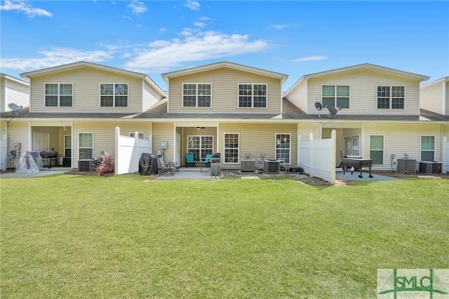 rear view of property featuring a patio, central AC unit, fence, and a lawn