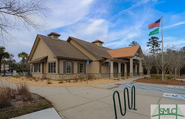 exterior space featuring stone siding, stucco siding, and fence