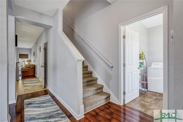 stairs with hardwood / wood-style flooring, washer / clothes dryer, and baseboards