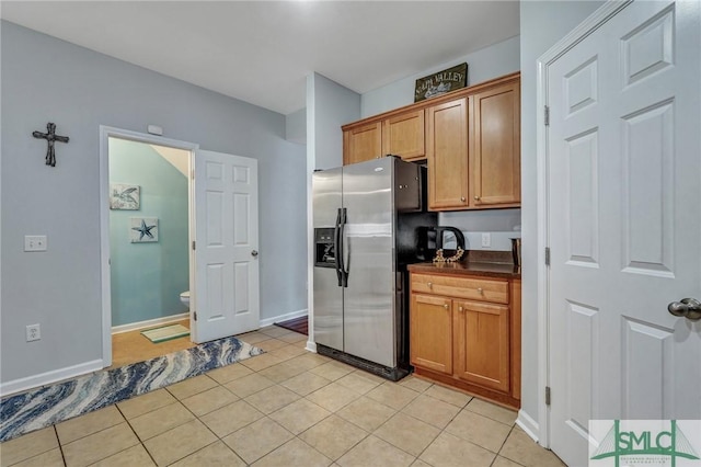 kitchen featuring dark countertops, stainless steel refrigerator with ice dispenser, and light tile patterned flooring