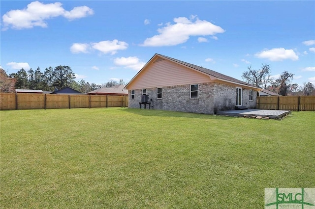 back of property featuring a yard, brick siding, a fenced backyard, and a patio area