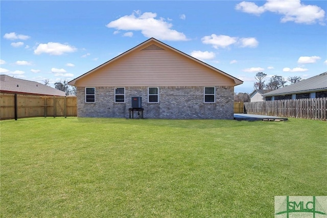 back of property featuring brick siding, a lawn, and a fenced backyard