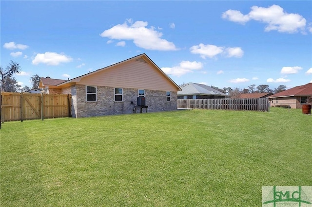 rear view of property with a lawn, brick siding, and a fenced backyard