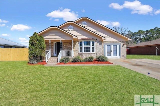 view of front of property with brick siding, covered porch, a front yard, and fence