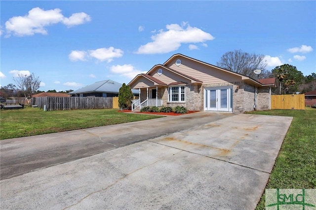 view of front of home featuring a front lawn, fence, concrete driveway, french doors, and a gate