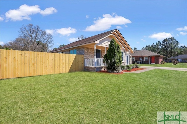 view of home's exterior with a yard, brick siding, a porch, and fence