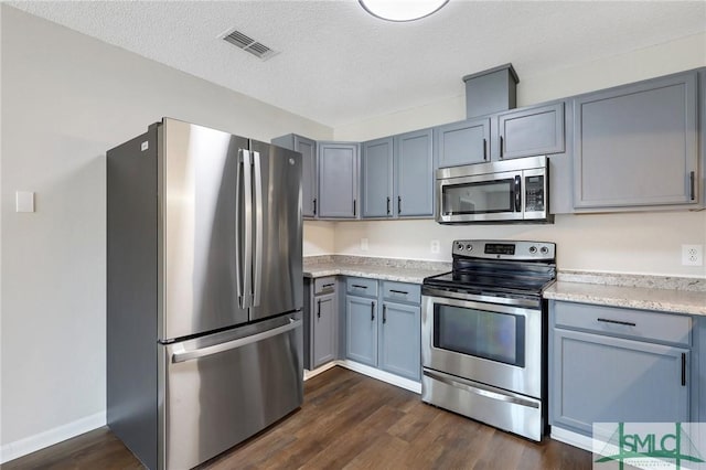 kitchen featuring visible vents, gray cabinets, stainless steel appliances, dark wood-style floors, and a textured ceiling