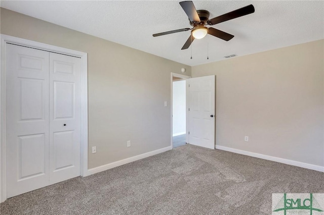 unfurnished bedroom featuring baseboards, ceiling fan, a closet, a textured ceiling, and carpet flooring