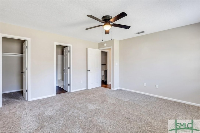 unfurnished bedroom featuring carpet, baseboards, visible vents, a spacious closet, and a textured ceiling