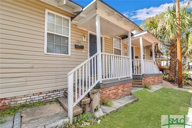 view of exterior entry featuring a yard and covered porch