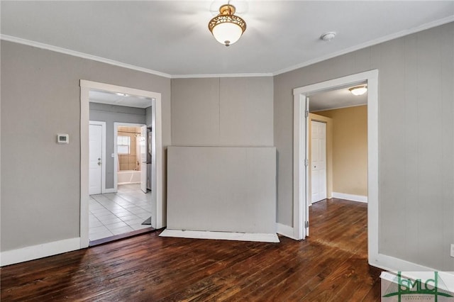 spare room with baseboards, dark wood-type flooring, and crown molding