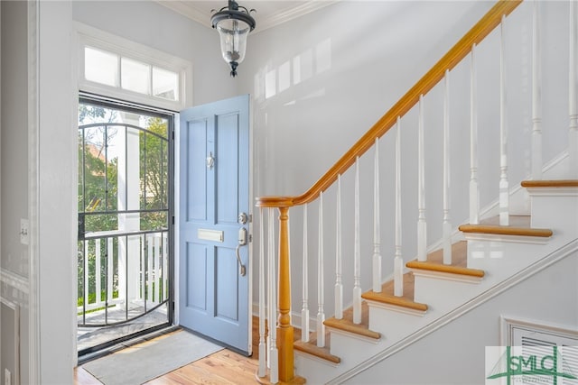 foyer entrance with stairway, wood finished floors, and ornamental molding