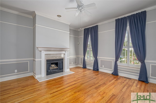 unfurnished living room with a decorative wall, crown molding, ceiling fan, and wood finished floors