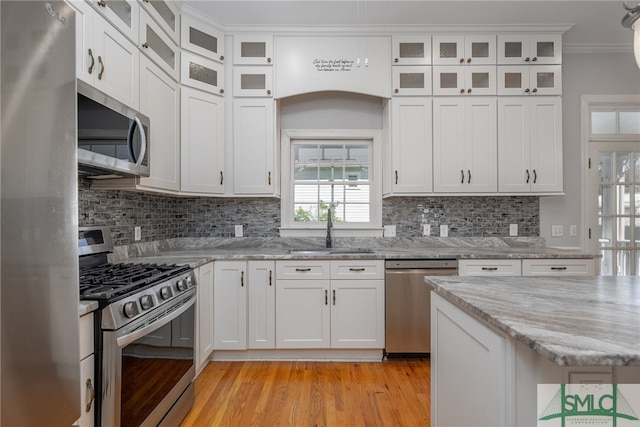 kitchen with tasteful backsplash, ornamental molding, light wood-style floors, stainless steel appliances, and a sink