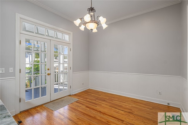 interior space featuring french doors, a chandelier, wainscoting, and light wood-style flooring