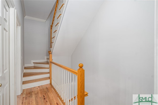 stairway featuring wood finished floors and ornamental molding