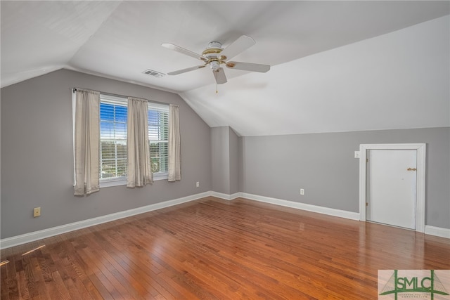 additional living space featuring visible vents, lofted ceiling, wood-type flooring, baseboards, and ceiling fan