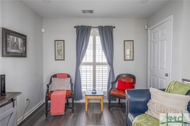 living area featuring visible vents, baseboards, and wood finished floors