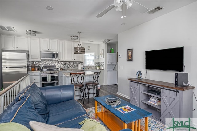 living area featuring visible vents, baseboards, dark wood-type flooring, and ceiling fan