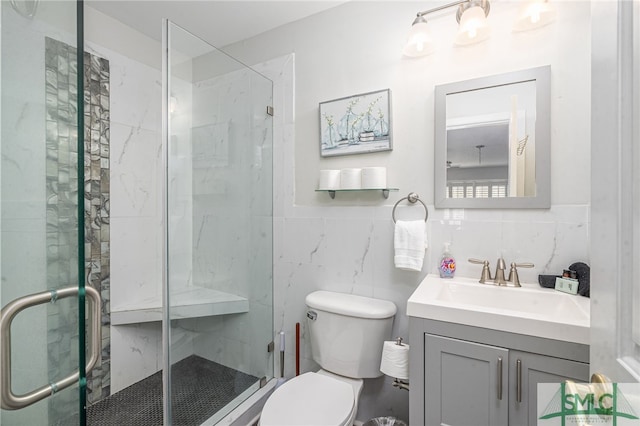 bathroom featuring toilet, a stall shower, vanity, and tile walls