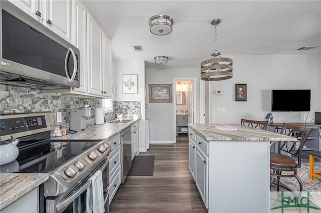 kitchen with visible vents, decorative backsplash, a kitchen breakfast bar, white cabinets, and stainless steel appliances