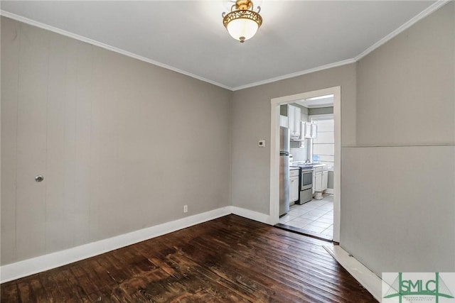 spare room with wood finished floors, baseboards, and ornamental molding